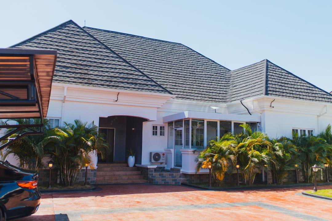 Exterior of Empyrean Shortlet, a white bungalow with palms in Rayfield, Jos